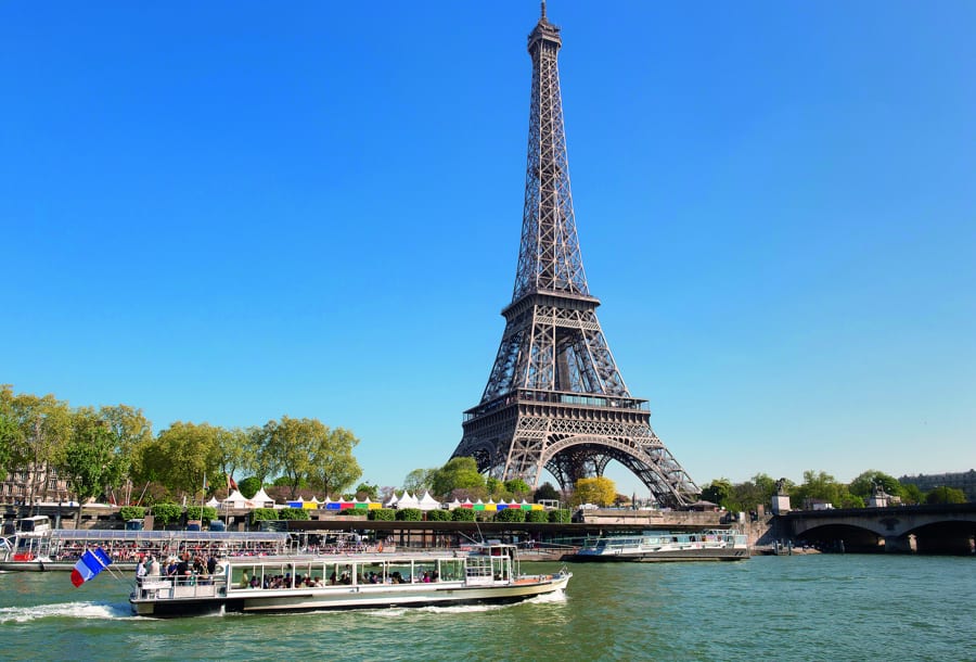Eiffelturm in Paris. Vor dem Eiffelturm der Fluss Seine mit einem Schiff Bateau-Mouche.