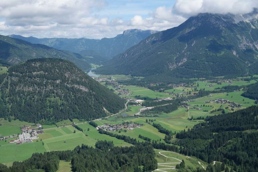 Spektakulärer Panoramablick auf die Kitzbüheler Alpen, den Wilden Kaiser, die Hohen Tauern, den Pillersee und die Waidringer Steinplatte vom Jakobskreuz. Weites Tal, grüne Almen, Berge mit grünen Nadelbäumen